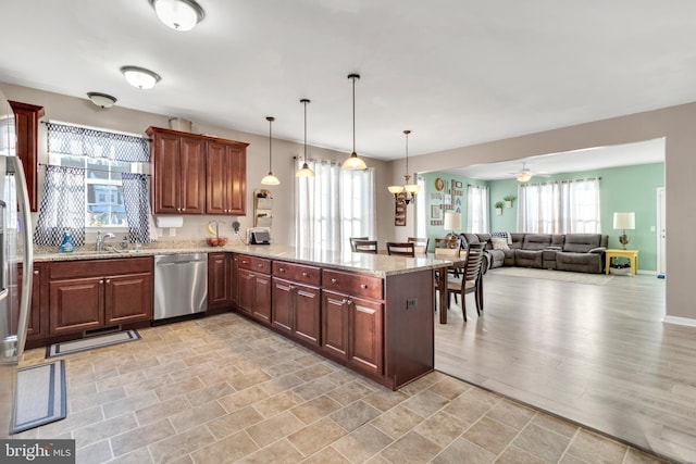 kitchen with decorative light fixtures, kitchen peninsula, plenty of natural light, and stainless steel dishwasher