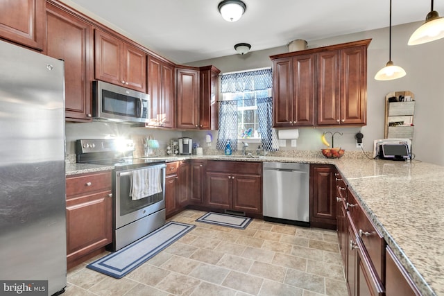 kitchen with sink, stainless steel appliances, light stone counters, and decorative light fixtures