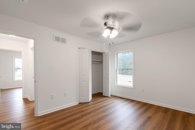 unfurnished bedroom featuring ceiling fan, dark hardwood / wood-style floors, and multiple windows