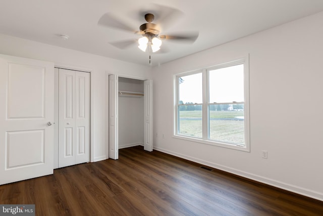 unfurnished bedroom with multiple closets, ceiling fan, and dark hardwood / wood-style floors