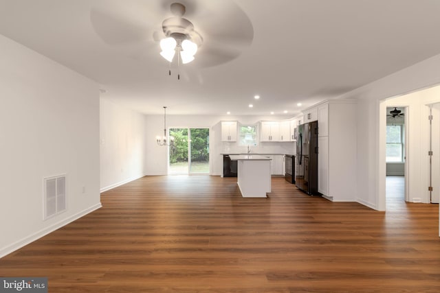 unfurnished living room featuring sink, ceiling fan with notable chandelier, and dark hardwood / wood-style floors