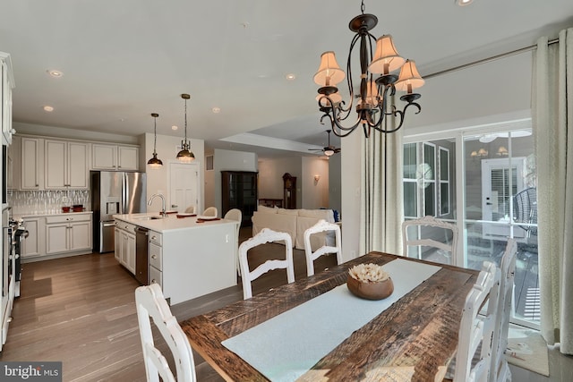 dining room featuring hardwood / wood-style flooring, ceiling fan with notable chandelier, and sink