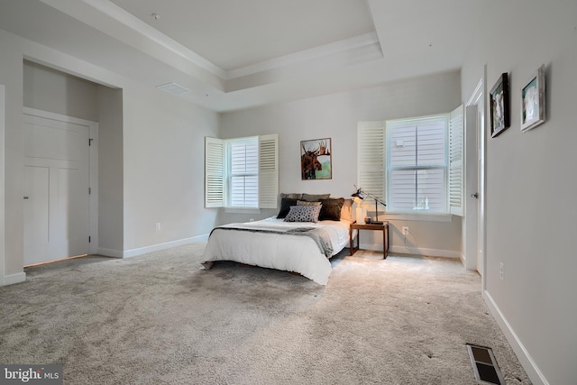 bedroom with light carpet, ornamental molding, and a raised ceiling