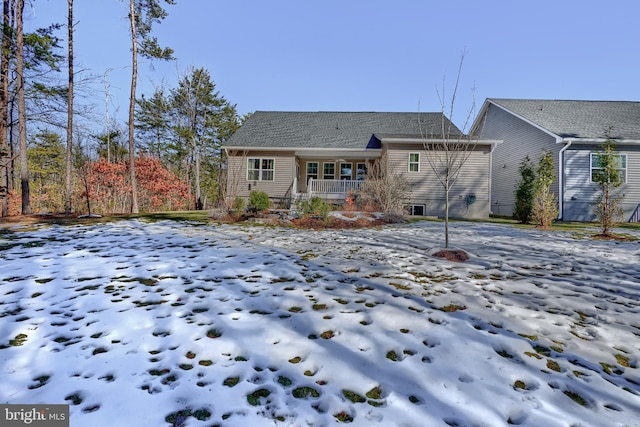 snow covered rear of property with a porch