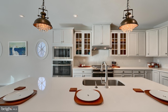 kitchen featuring pendant lighting, appliances with stainless steel finishes, sink, and white cabinets