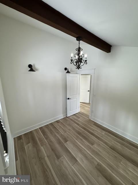 spare room with dark hardwood / wood-style flooring, a chandelier, and beamed ceiling