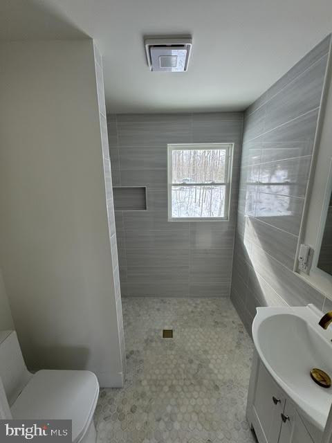 bathroom with vanity, toilet, and tiled shower