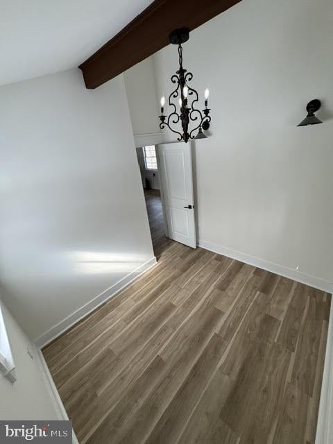 unfurnished dining area featuring hardwood / wood-style flooring, a notable chandelier, and lofted ceiling with beams