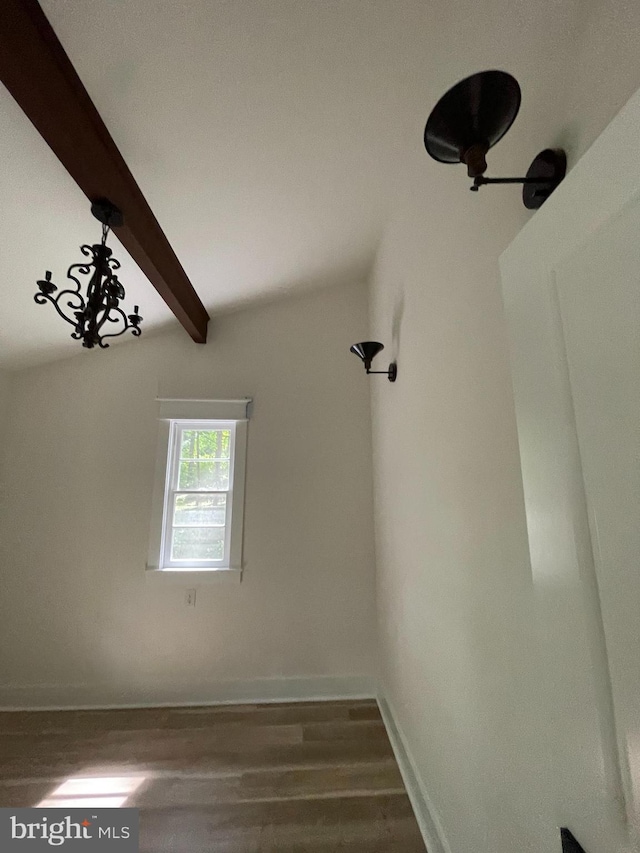 empty room featuring dark hardwood / wood-style flooring and vaulted ceiling with beams