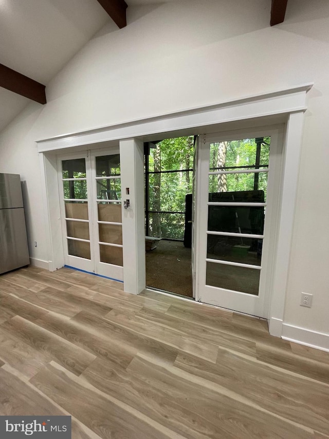 entryway featuring hardwood / wood-style floors, a wealth of natural light, lofted ceiling with beams, and french doors