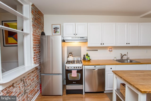 kitchen featuring appliances with stainless steel finishes, wooden counters, white cabinetry, sink, and light wood-type flooring