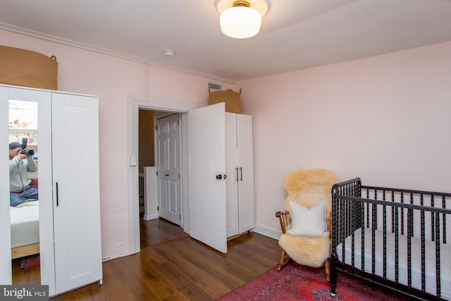 bedroom featuring a crib and dark hardwood / wood-style flooring