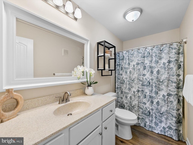 bathroom with hardwood / wood-style flooring, vanity, curtained shower, and toilet