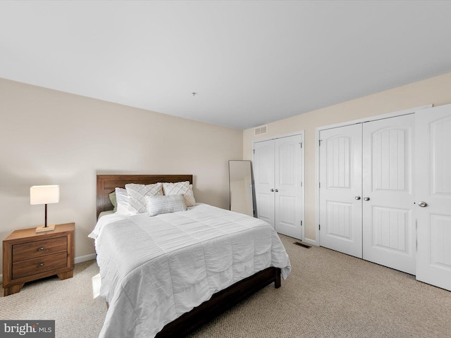 bedroom featuring multiple closets and light carpet