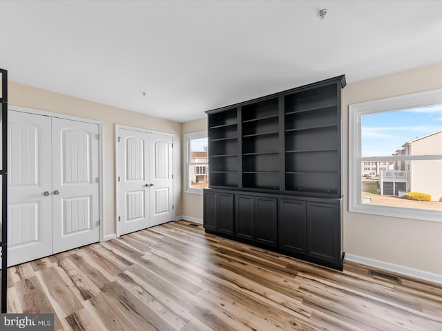 unfurnished bedroom featuring two closets and light hardwood / wood-style floors