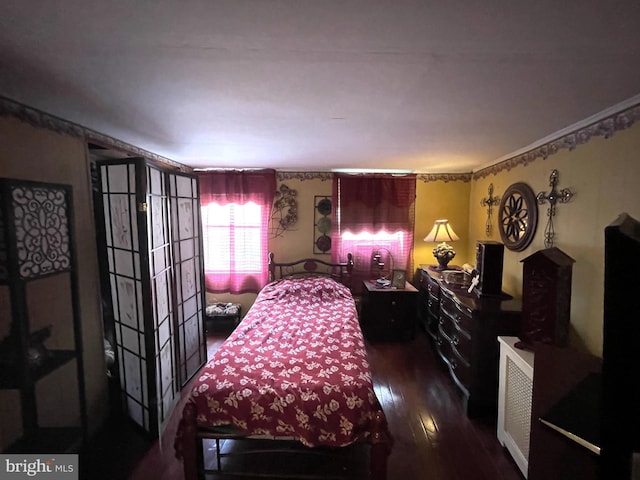 bedroom with ornamental molding and dark hardwood / wood-style floors