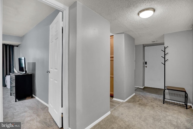 hall with light colored carpet and a textured ceiling