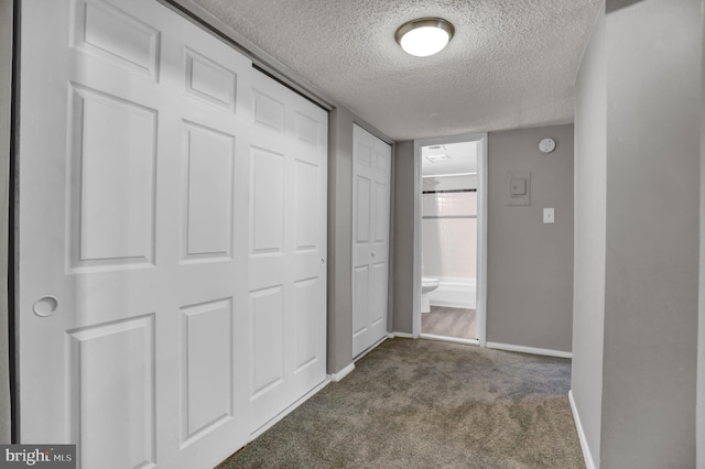 hallway featuring a textured ceiling and carpet floors