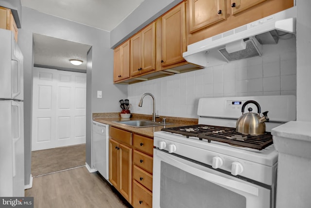 kitchen featuring white appliances, light brown cabinetry, decorative backsplash, sink, and light hardwood / wood-style flooring