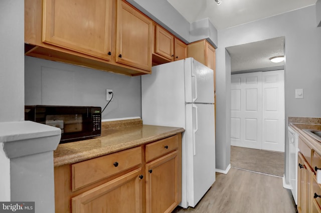 kitchen featuring light brown cabinetry, white appliances, and light hardwood / wood-style flooring