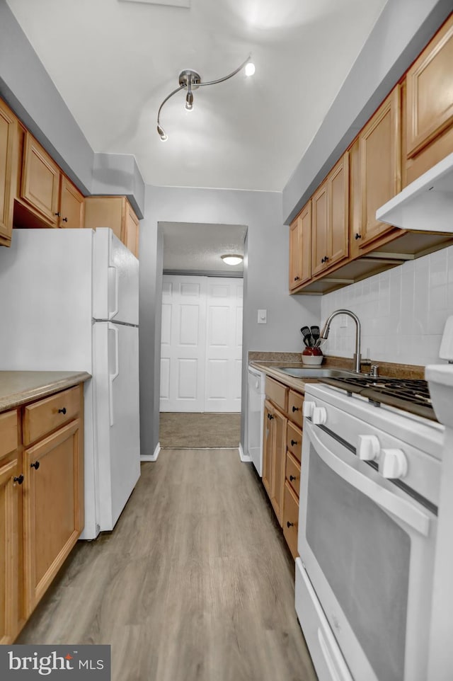 kitchen with white appliances, tasteful backsplash, light hardwood / wood-style floors, sink, and light brown cabinetry