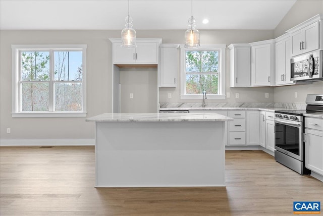 kitchen with white cabinets, stainless steel appliances, a kitchen island, and decorative light fixtures