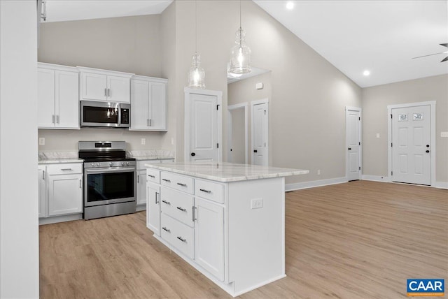 kitchen featuring light stone countertops, appliances with stainless steel finishes, white cabinets, a kitchen island, and high vaulted ceiling