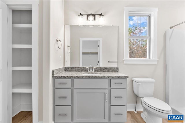 bathroom featuring built in features, wood-type flooring, toilet, and vanity