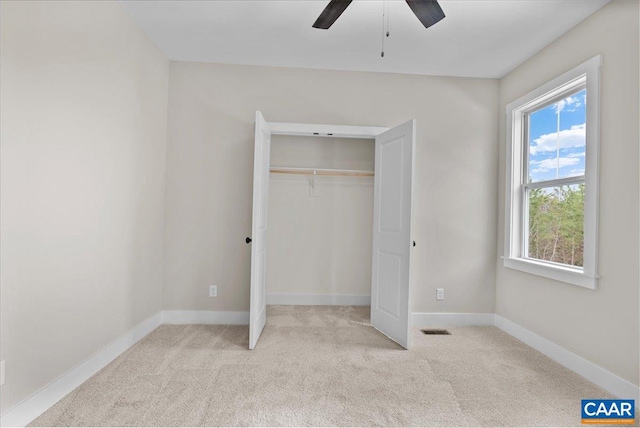 unfurnished bedroom featuring ceiling fan, a closet, and light carpet