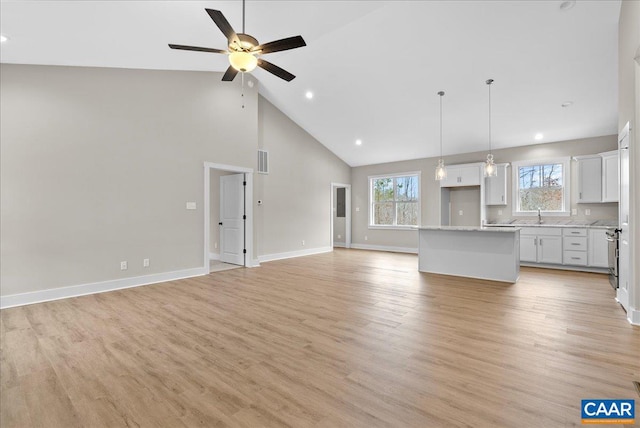 unfurnished living room with sink, ceiling fan, high vaulted ceiling, and light hardwood / wood-style floors