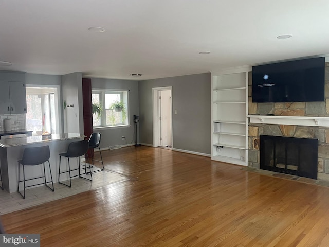 living room with light hardwood / wood-style floors and a stone fireplace