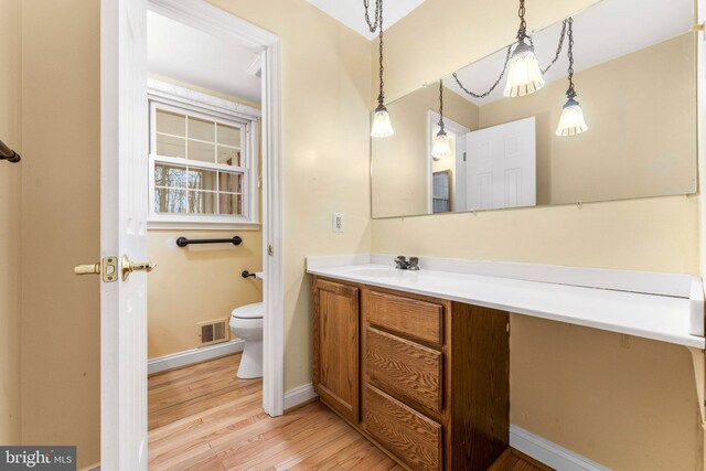 bathroom with wood-type flooring, vanity, and toilet