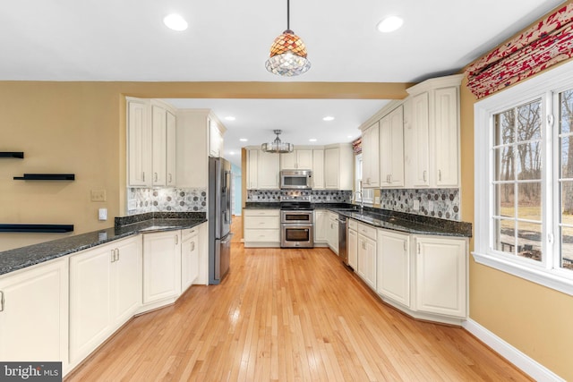 kitchen featuring hanging light fixtures, backsplash, a wealth of natural light, and appliances with stainless steel finishes