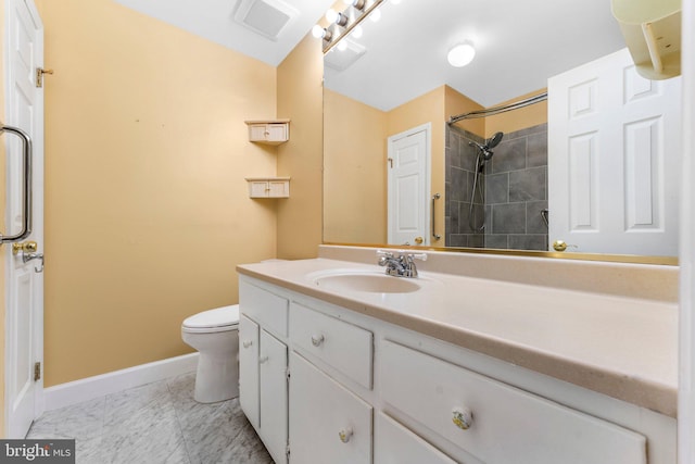 bathroom with tiled shower, vanity, and toilet