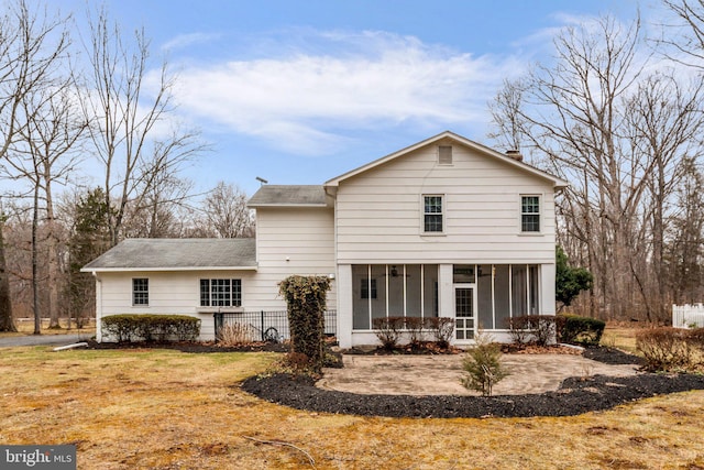 rear view of house featuring a patio, a sunroom, and a lawn