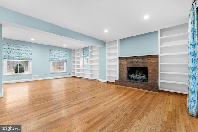 unfurnished living room featuring a fireplace, built in features, light hardwood / wood-style floors, and beamed ceiling