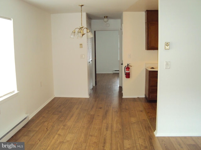 interior space with hardwood / wood-style flooring, a baseboard heating unit, and a notable chandelier