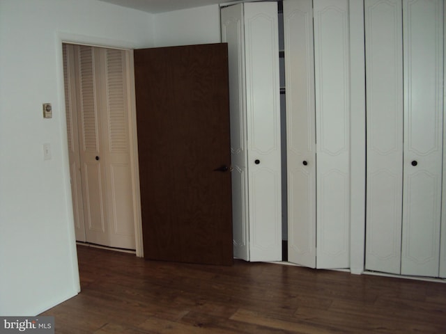 unfurnished bedroom with dark wood-type flooring and two closets