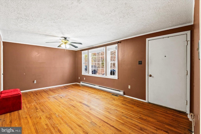 spare room featuring crown molding, ceiling fan, baseboard heating, hardwood / wood-style floors, and a textured ceiling