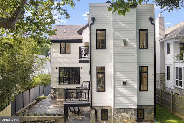 3819 NW Albemarle St NW, Washington, DC 20016 - rear view of house with a balcony, a fenced backyard, stone siding, and a patio
