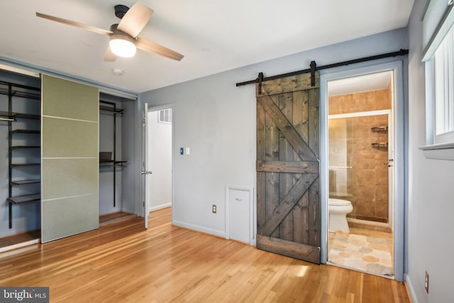 906 N Belgrade Rd, Silver Spring, MD 20902 - unfurnished bedroom featuring a barn door, wood finished floors, connected bathroom, baseboards, and a closet