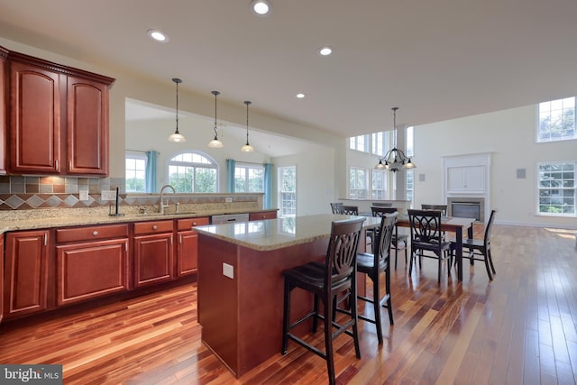 kitchen with sink, a breakfast bar area, hanging light fixtures, a kitchen island, and decorative backsplash