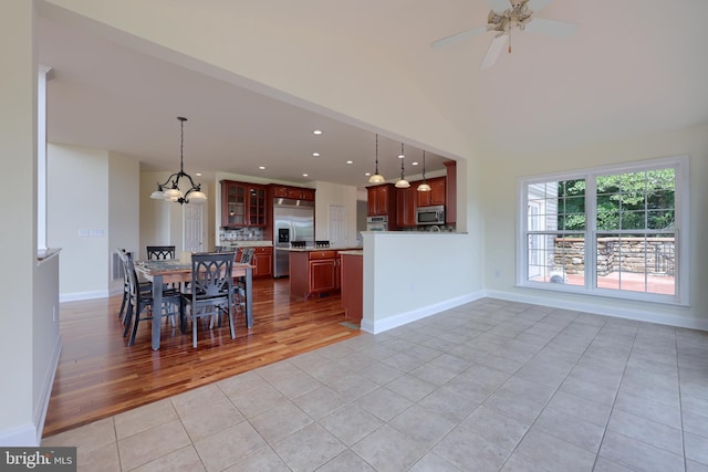 unfurnished dining area with light tile patterned flooring, ceiling fan with notable chandelier, and vaulted ceiling