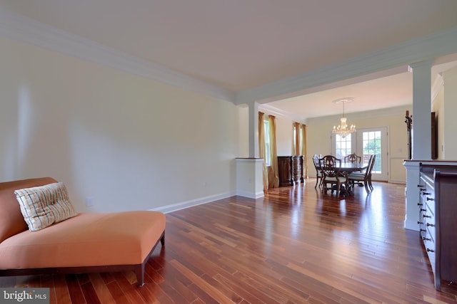 sitting room featuring ornamental molding, dark hardwood / wood-style flooring, a chandelier, and decorative columns