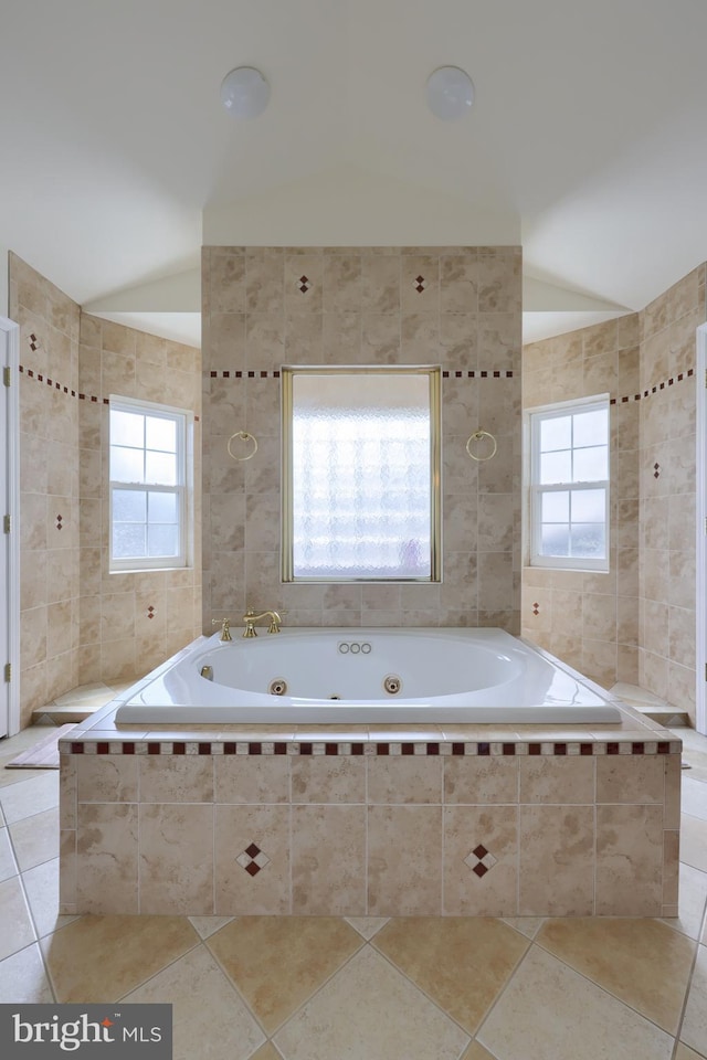 bathroom with a healthy amount of sunlight, tile patterned flooring, vaulted ceiling, and tiled tub