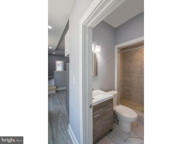 bathroom with vanity, toilet, and a tile shower