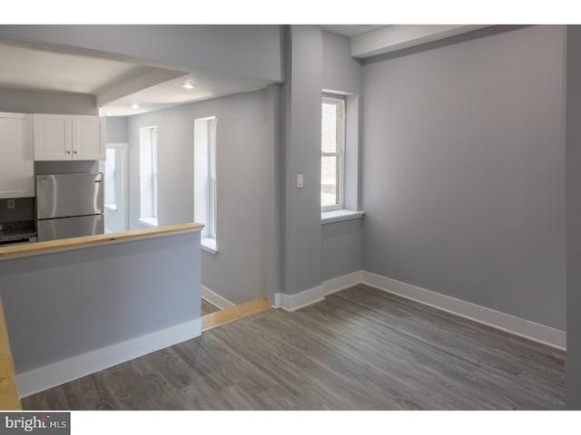 kitchen with dark hardwood / wood-style floors, stainless steel fridge, and white cabinets