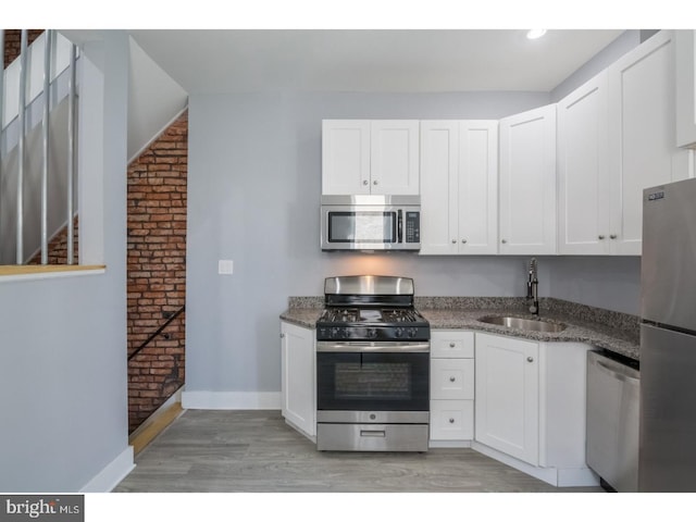 kitchen featuring appliances with stainless steel finishes, sink, white cabinets, and light hardwood / wood-style flooring