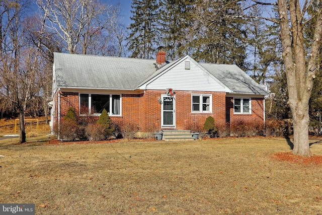 view of front of house featuring a chimney, a front lawn, and brick siding