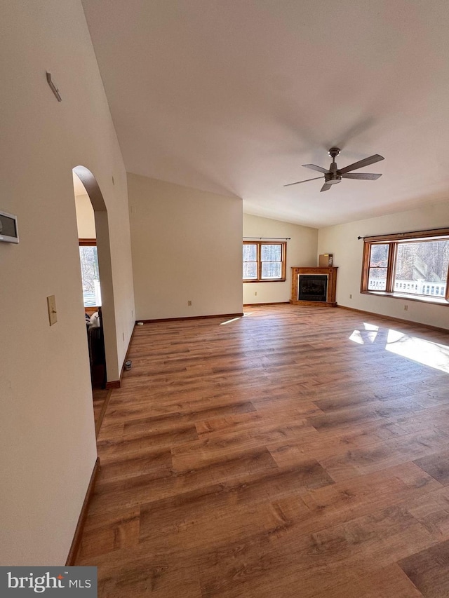 unfurnished living room with plenty of natural light, dark wood-type flooring, and ceiling fan